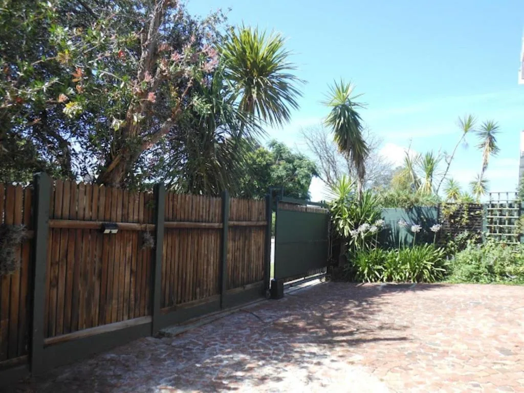 Wooden driveway gates with palm trees and brick paving entrance