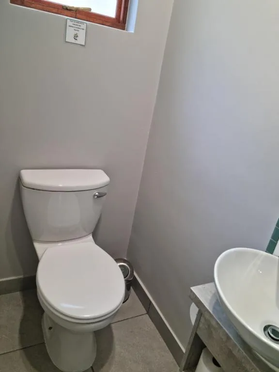 Clean white toilet in bright bathroom with tiled floor and small window