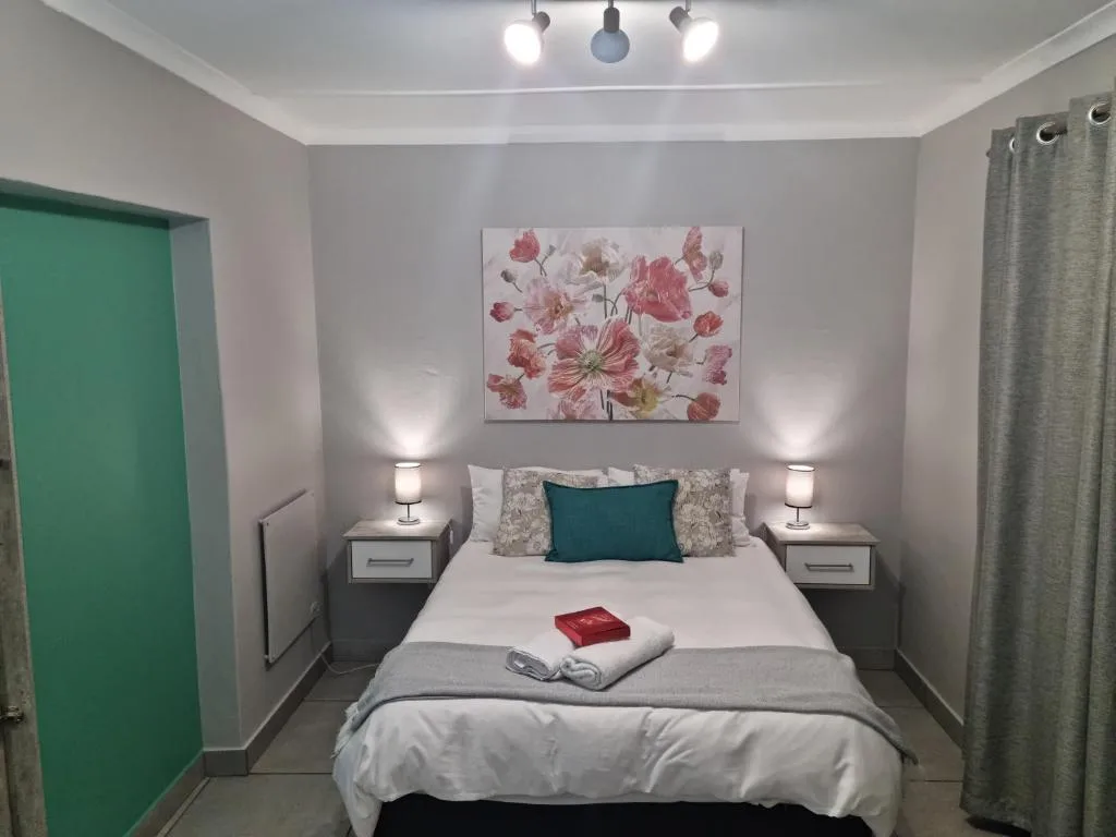 Bright bedroom with queen bed, floral artwork, matching bedside lamps and tables