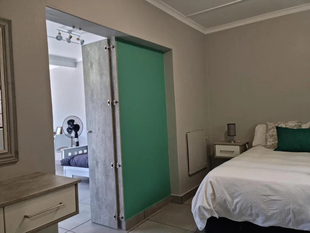 Spacious bedroom with queen bed, green accent wall, and en-suite bathroom access