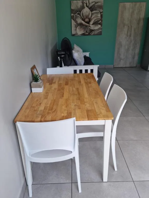 Wooden dining table with white chairs in modern green-walled interior