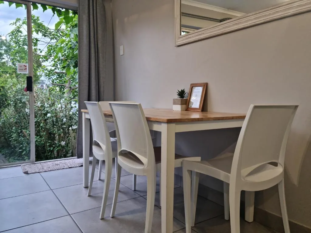 Modern dining table with cream chairs and garden view through glass doors