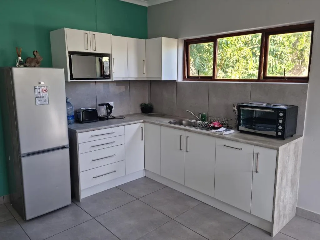 Modern kitchen with white cabinetry, stainless steel appliances, and garden views