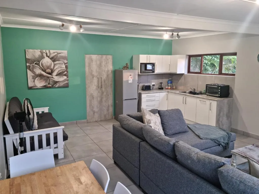 Open-plan lounge with gray sofa, turquoise accent wall, and integrated kitchen