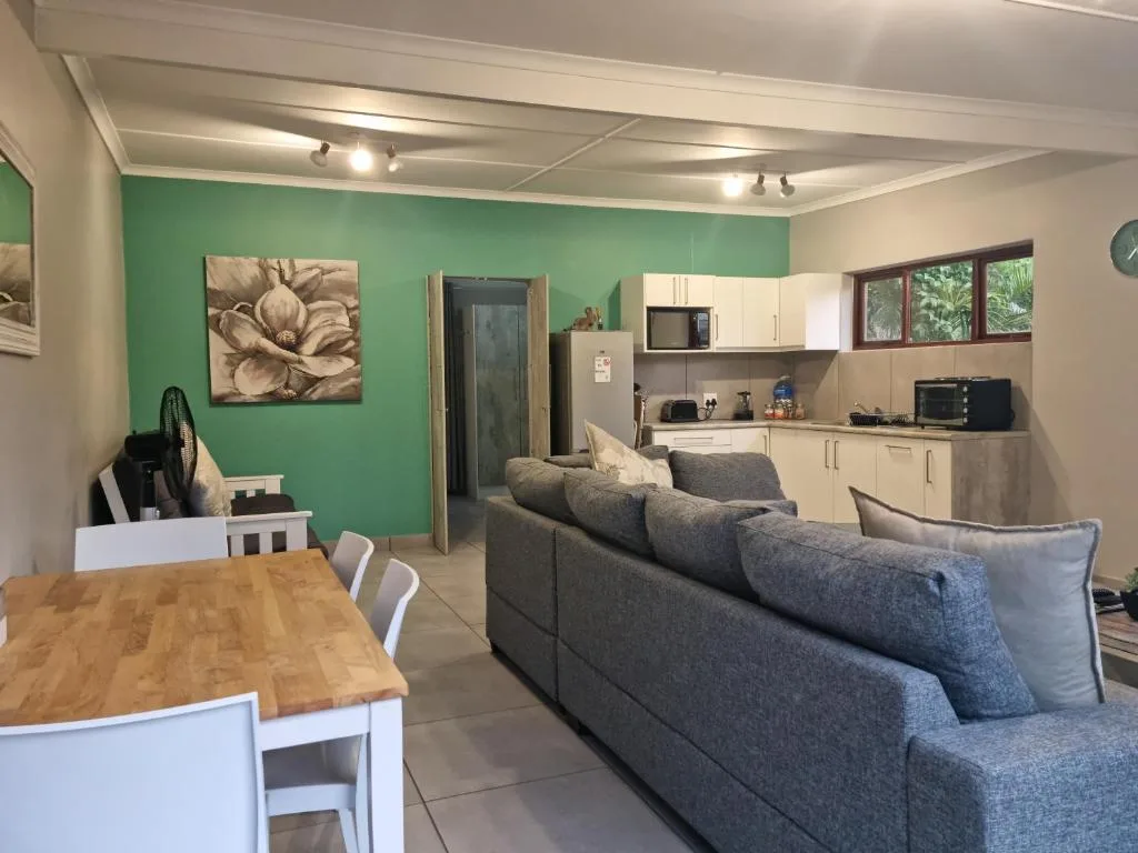 Open-plan lounge with gray sofa, dining table, and kitchen area visible