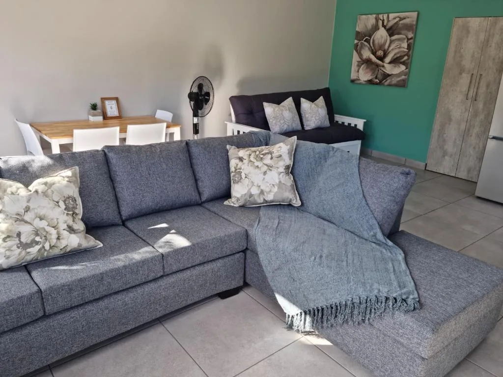 Spacious lounge with grey sectional sofa, decorative pillows, and dining area visible
