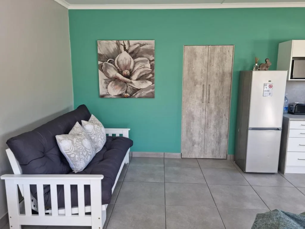 Open-plan lounge with turquoise accent wall, dark sofa, and kitchen area visible