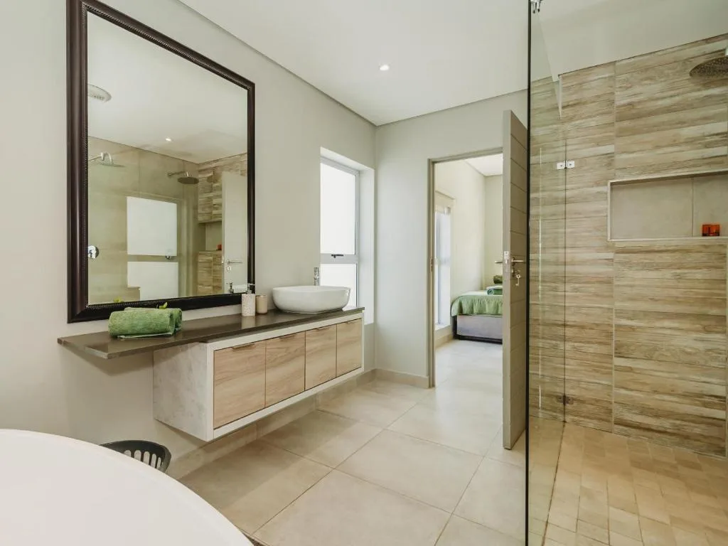 Modern bathroom with vanity sink, large mirror, and walk-in shower enclosure