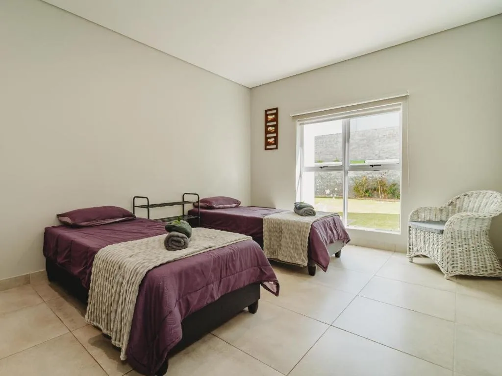 Spacious bedroom with multiple beds and scenic garden views through large windows