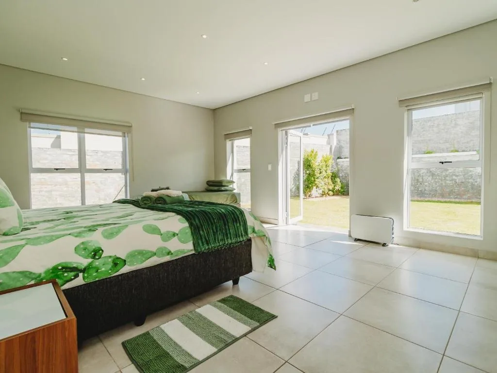 Spacious master bedroom with green bedding and garden views through sliding doors