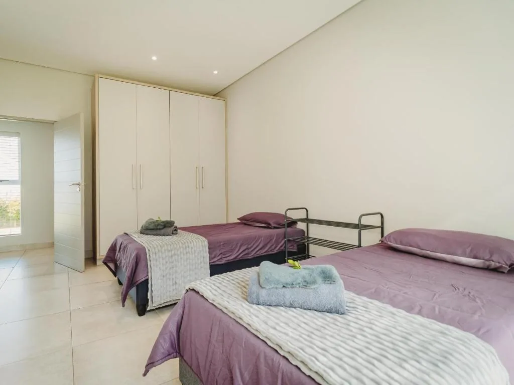 Spacious bedroom with three beds, built-in wardrobe, and tiled flooring
