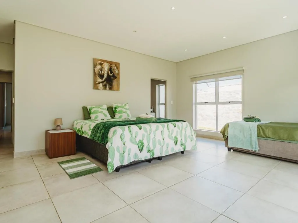 Bright bedroom with green leaf patterned bedding and large windows