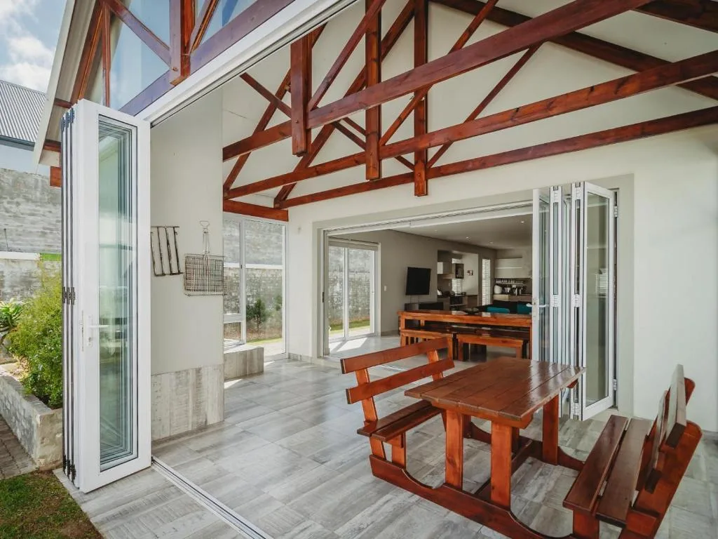Modern covered deck with wooden beams and dining table overlooking garden