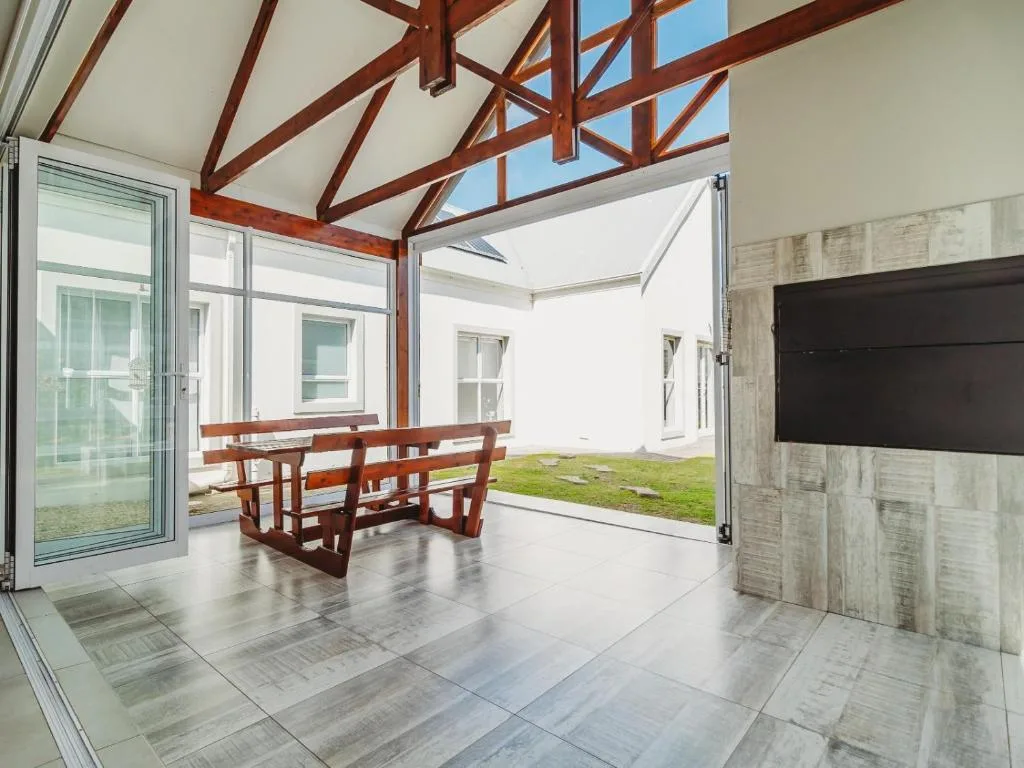 Modern covered patio with wooden beams, built-in seating, and garden views