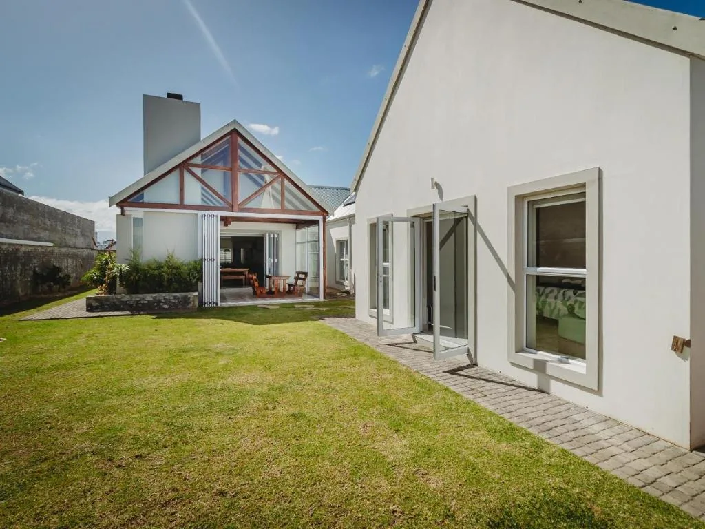 Modern white cottage with gabled porch and manicured lawn garden