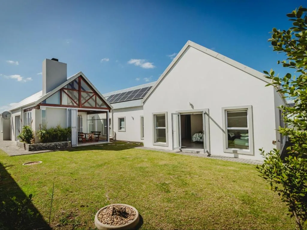 Modern white holiday home with manicured garden and clear blue sky