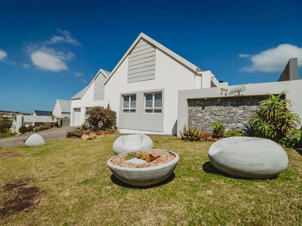 Modern white holiday home with manicured garden and decorative concrete fire pit seating