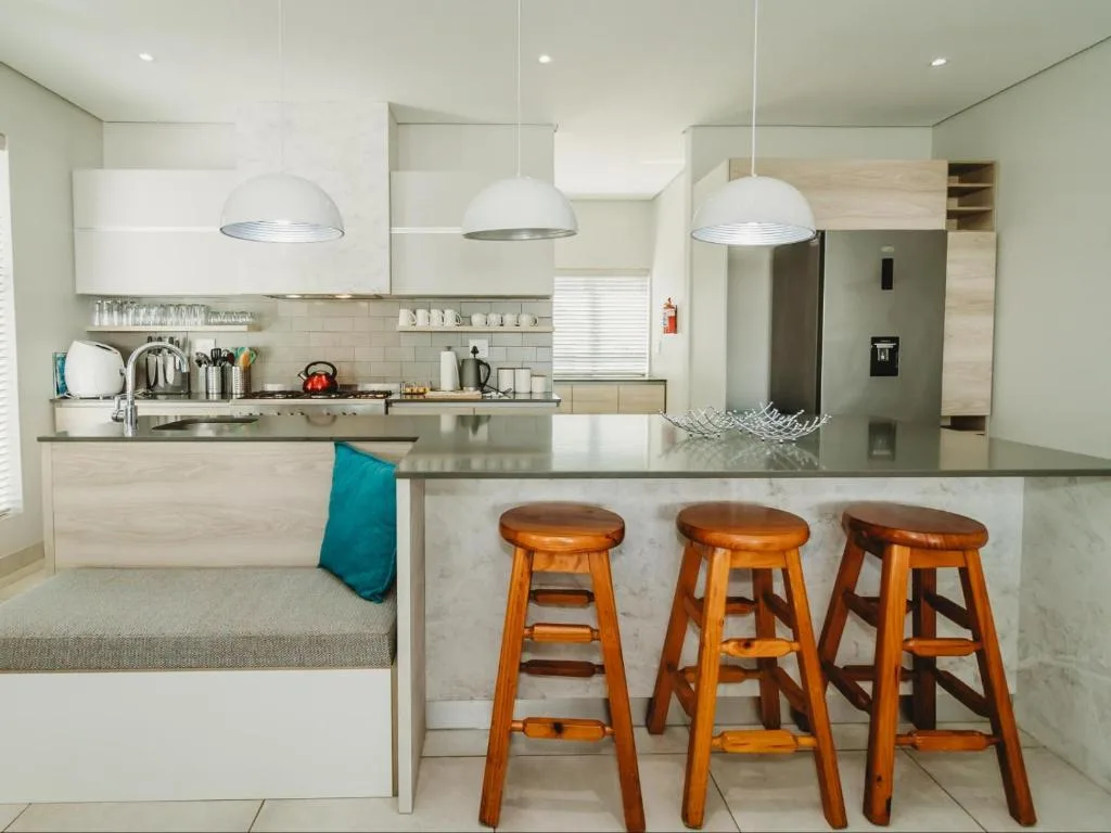 Modern kitchen with white cabinetry, stainless steel appliances, and wooden bar stools
