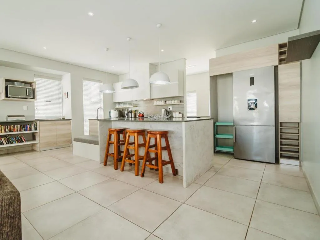 Modern open-plan kitchen with island, wooden bar stools, stainless steel appliances