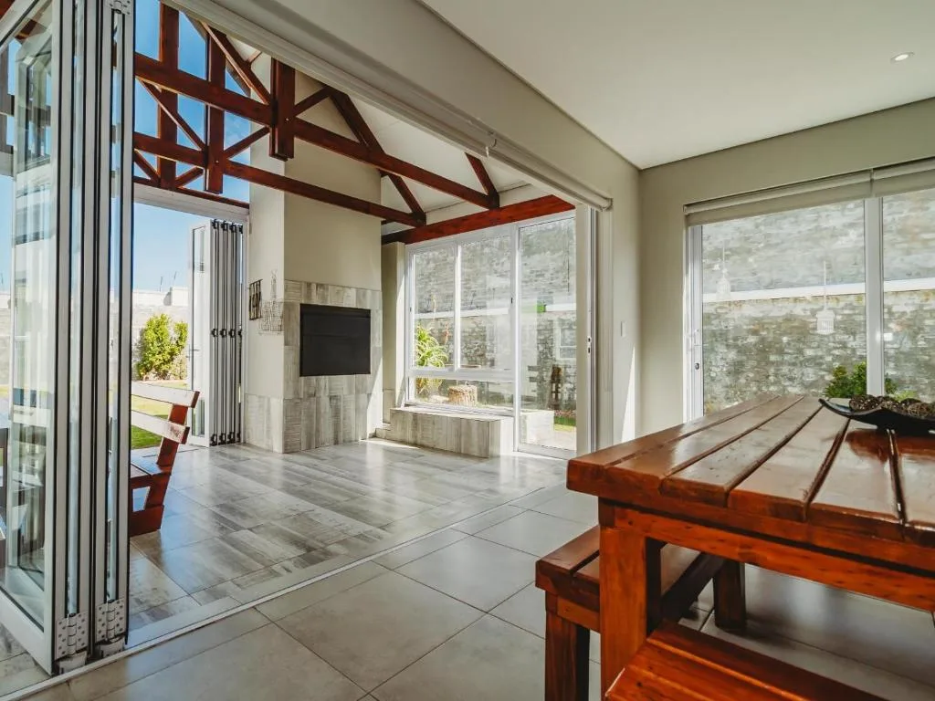 Modern lounge with wooden beams, TV wall, and sliding glass doors opening to patio