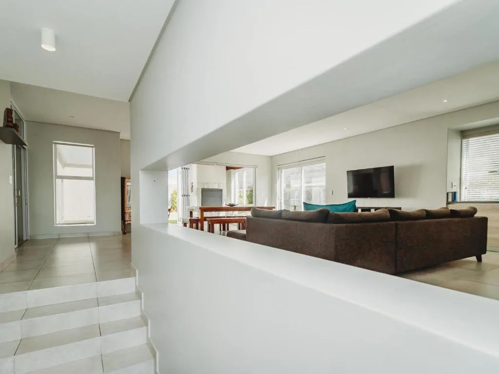 Spacious open-plan lounge with brown sofa and wall-mounted television
