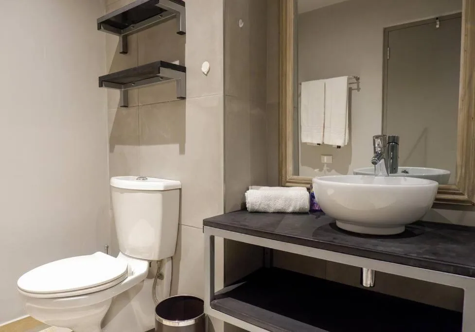 Modern bathroom with round white basin sink and toilet on dark vanity