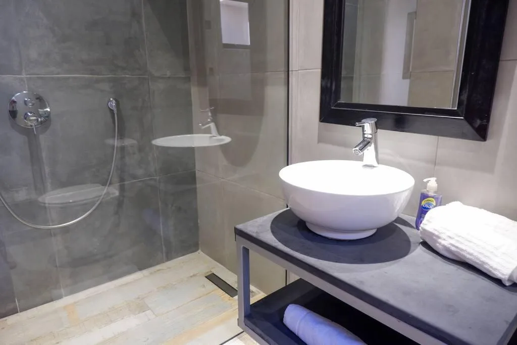 Modern bathroom with vessel sink, glass shower enclosure, and black-framed mirror