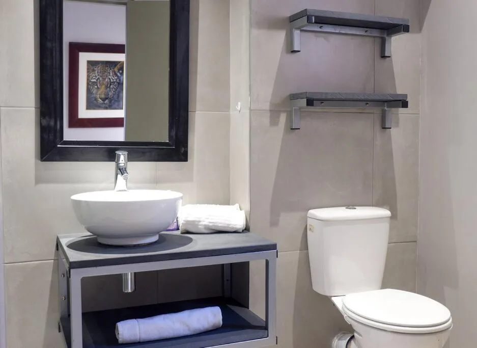 Modern bathroom with round white basin sink, toilet, and framed mirror