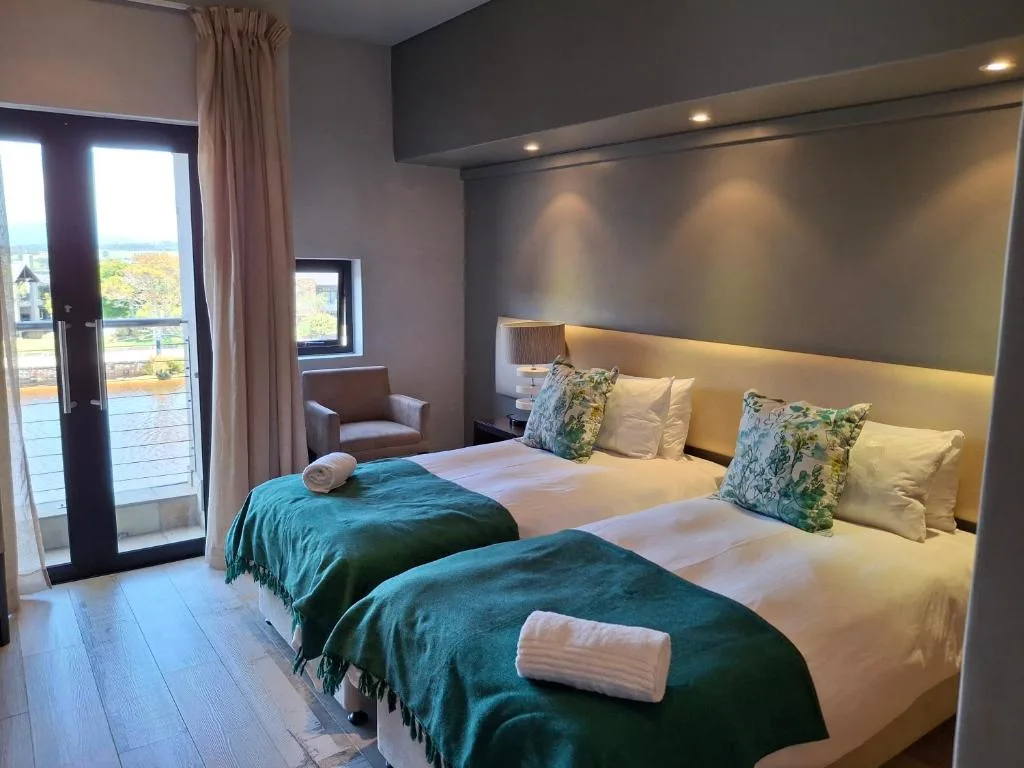 Modern twin bedroom with green throws, accent lighting, and garden view doors