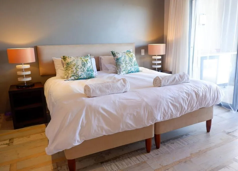 Spacious bedroom with twin beds, floral pillows, bedside lamps, and sliding doors