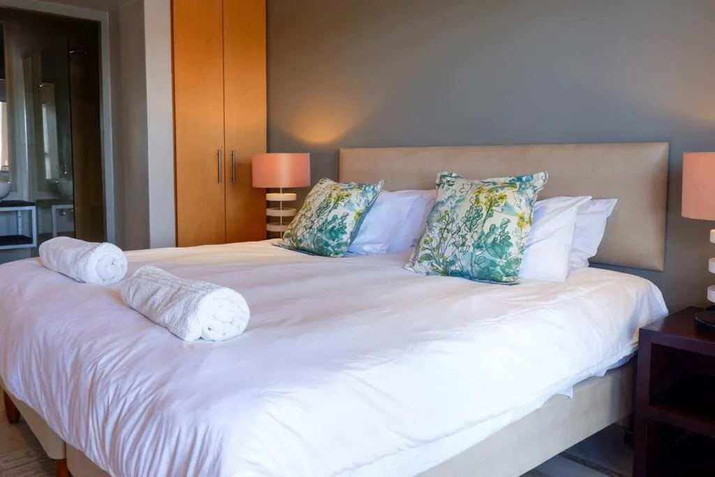 Spacious bedroom with king bed, floral pillows, and warm lighting