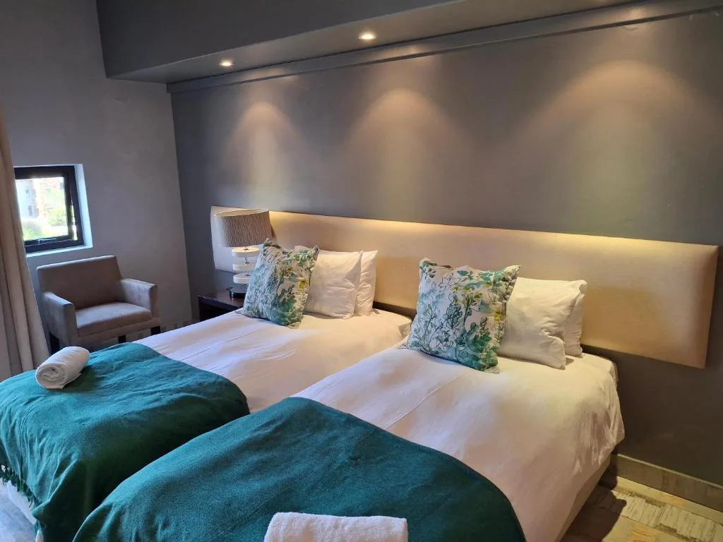 Modern bedroom with two beds, decorative pillows, and ambient lighting