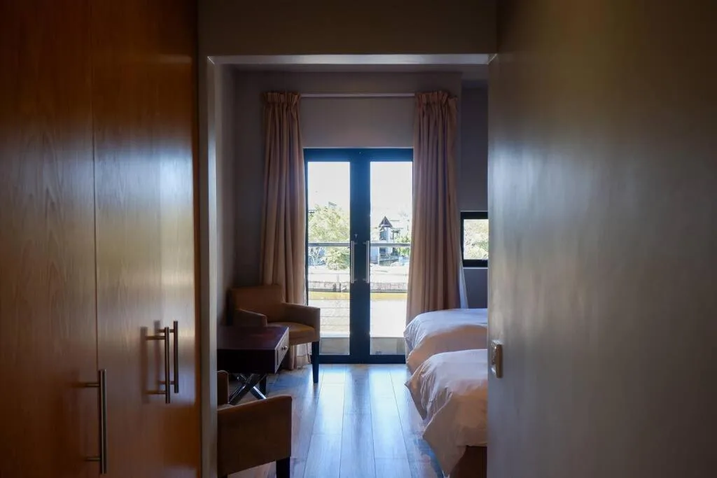 Bright bedroom with twin beds, glass doors opening to scenic balcony view