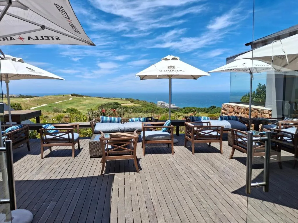 Spacious wooden deck with lounge chairs, umbrellas, and ocean view beyond