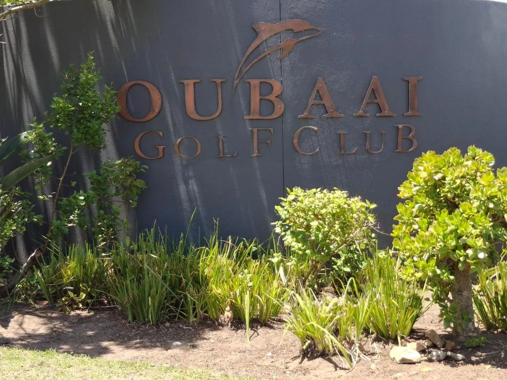 Oubaai Golf Club signage with lush green landscaping and plants