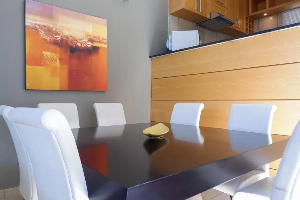 Modern dining table with white chairs and contemporary artwork above