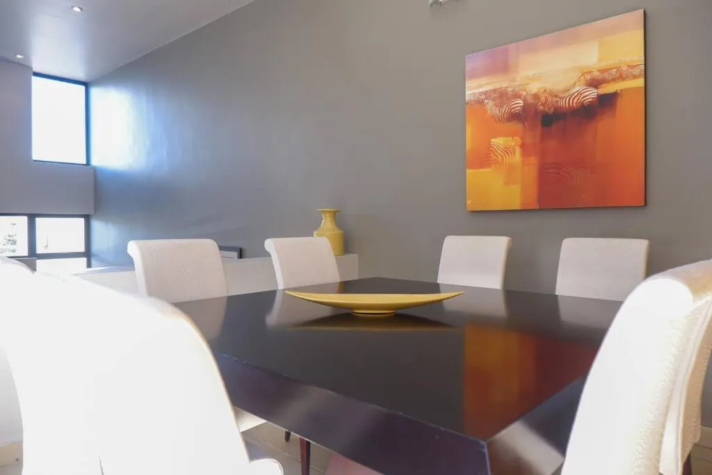 Modern dining room with black table, white chairs, and contemporary artwork