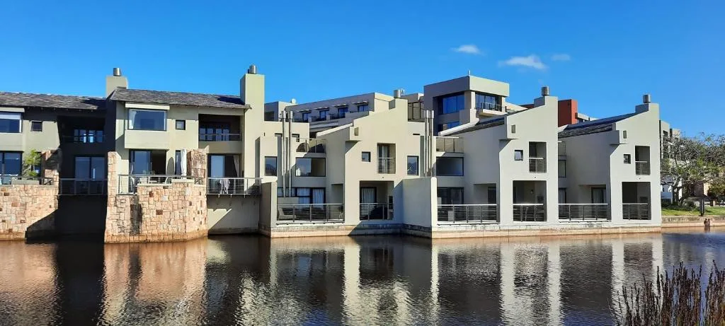 Modern waterfront apartment complex with cream facades reflecting in lagoon water