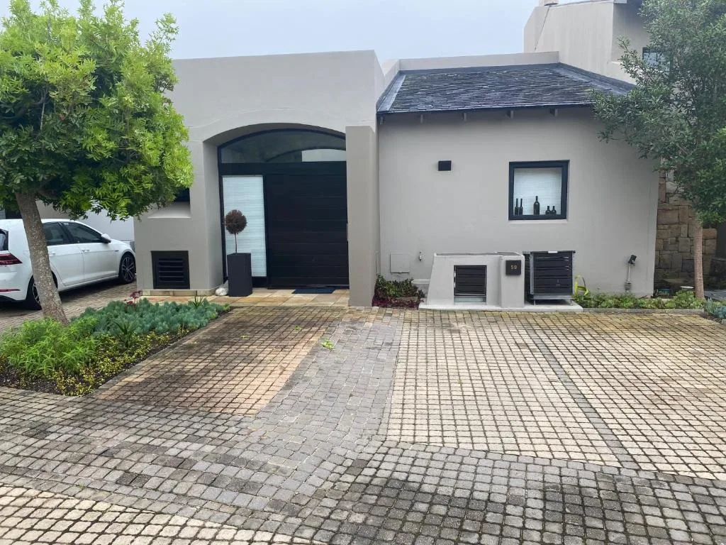 Modern white property with curved black entrance door and paved driveway