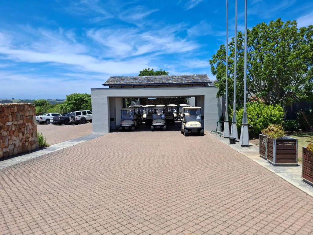 Modern carport with golf carts and paved driveway under clear blue sky
