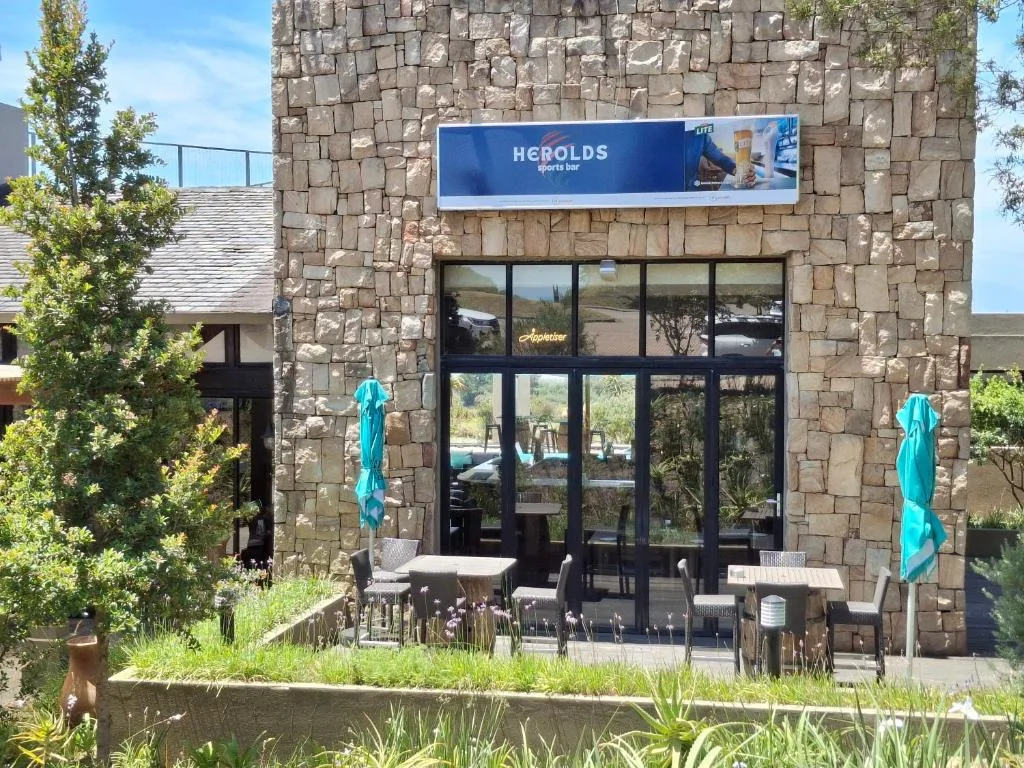 Stone facade building entrance with outdoor seating area and signage