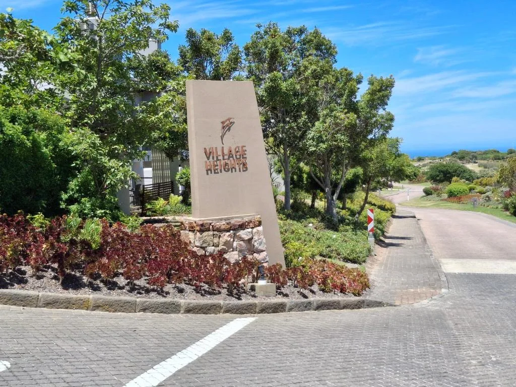 Village Heights entrance sign with landscaped gardens and tree-lined driveway