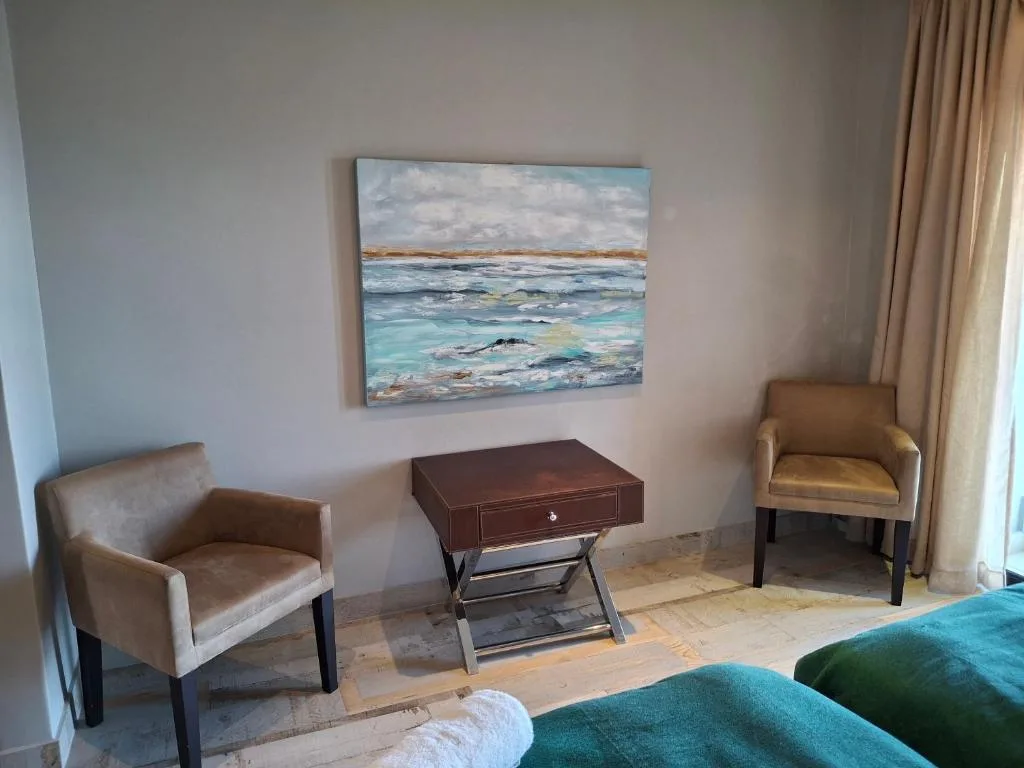 Modern lounge area with two upholstered chairs and coastal artwork above