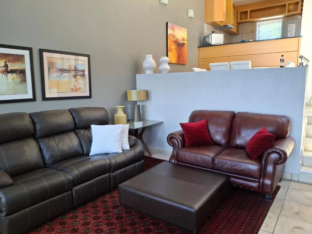 Spacious living room with leather sofas, framed artwork, and open-plan kitchen.