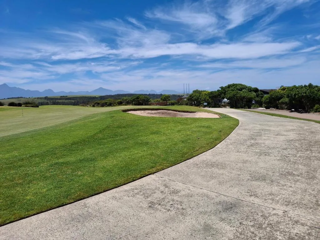 Scenic golf course landscape with distant mountains under blue sky
