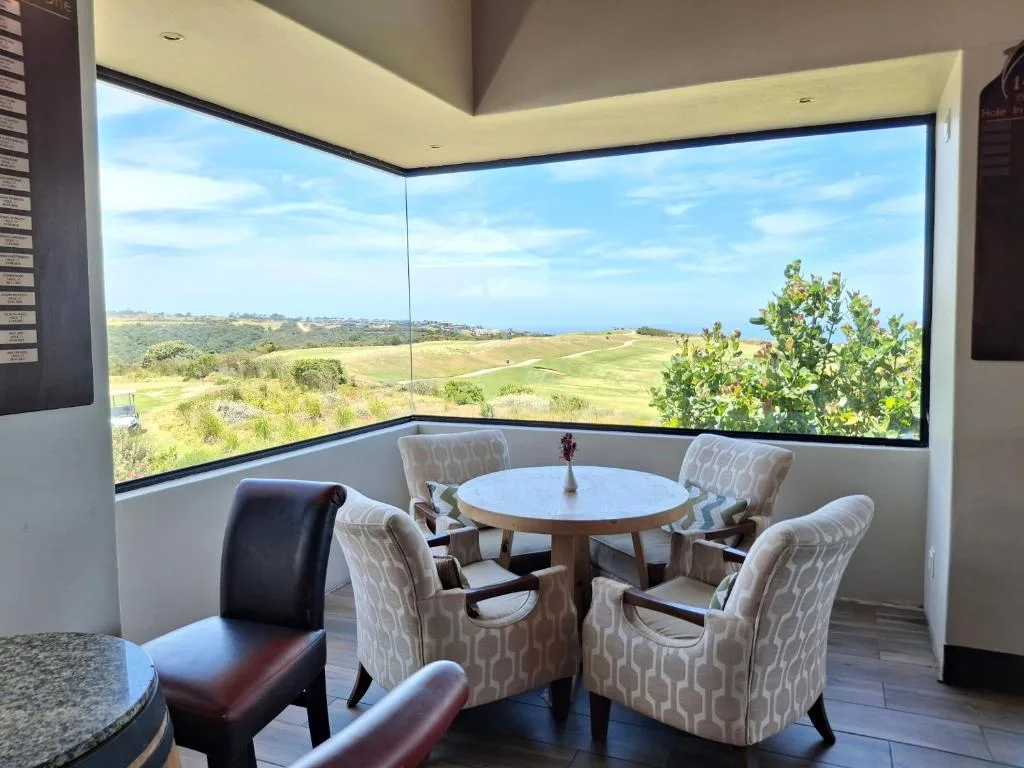 Panoramic landscape and ocean vista from modern dining area with floor-to-ceiling windows