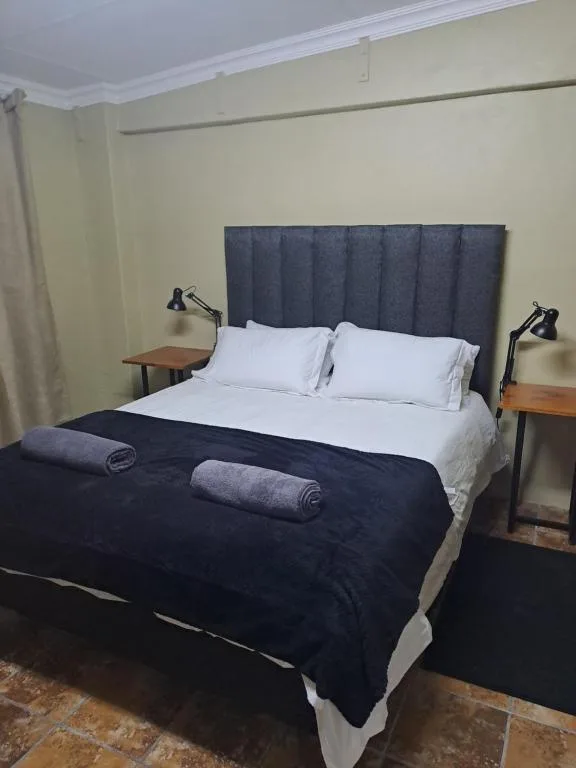 Neatly made bed with white linens and dark navy blanket in bright room