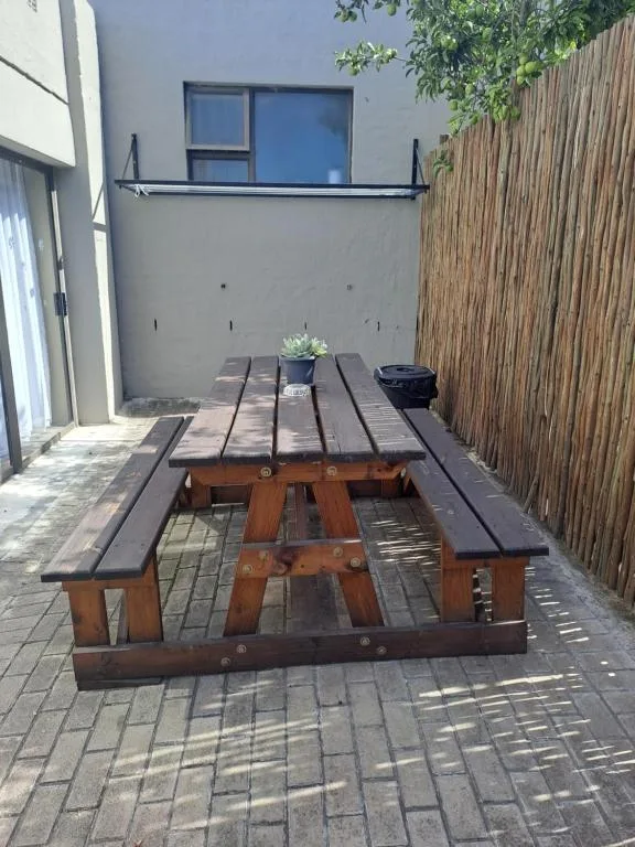 Wooden picnic table and benches on paved courtyard patio area