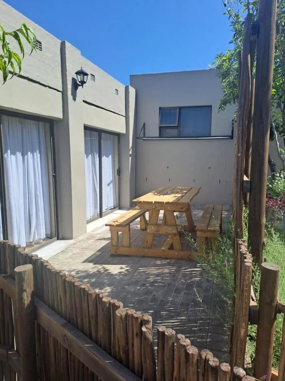 Wooden picnic table on paved patio beside modern apartment building