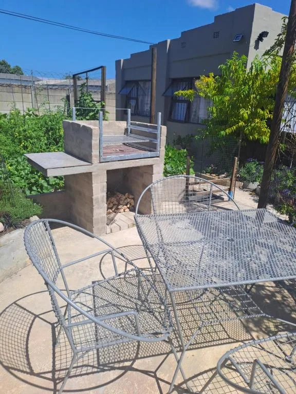 Outdoor patio with metal seating and braai area attached to house